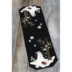 a black necktie with white snowmen and trees on it, sitting on a wooden floor