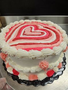 a heart shaped cake with white frosting and red icing