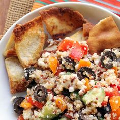 a white bowl filled with salad and bread on top of a striped table cloth next to a fork