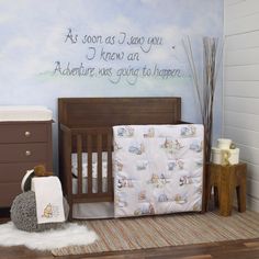 a baby's room with a crib, dresser and wall mural