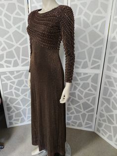 This late  1960s dress is so beautifully beaded with pinky brown pearls and bronze beads in a diagonal pattern on the bodice and they continue down the sleeves to wrist length. You would be sure to get lots of compliments wearing this stunning dress The label is Vie Victoria Royal of Hong Kong from the 60s. The bronze lurex dress has a high neckline, fitted bodice and waist then skims the hips to an A line skirt to ankle length The dress has a back nylon zipper, has small shoulder pads to help w Party Floor-length Brown Dress, Fitted Brown Evening Dress For Party, Brown Fitted Evening Dress For Party, Beaded Floor-length Maxi Dress For Party, Brown Floor-length Maxi Dress For Evening, Brown Floor-length Evening Dress, Elegant Brown Evening Dress For Formal Occasions, Fitted Brown Evening Dress, Elegant Brown Sequin Dress