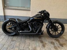 a black motorcycle parked on top of a brick road next to a building with windows