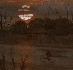 a person riding a bike down a street at night with the sun setting in the background