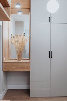 a white cabinet sitting next to a window in a room with wooden floors and walls