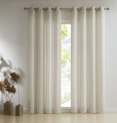 an open window with white curtains and plants in vases on the floor next to it