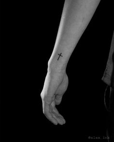 a person with a cross tattoo on their left arm holding the hand of another person