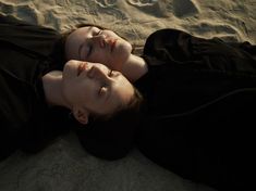 a woman laying on the sand with her eyes closed