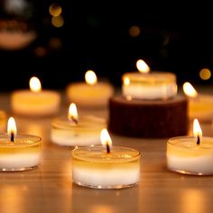 many lit candles sitting on top of a wooden table