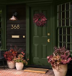 two large planters with flowers in front of a green door