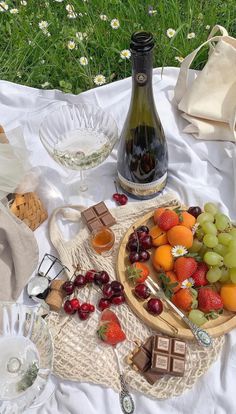 a bottle of wine sitting on top of a table next to fruit and chocolates