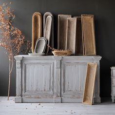 an old white cabinet with many pieces of furniture on top of it and a plant in the corner