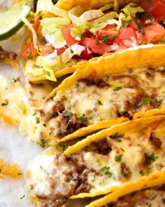 three tacos with meat, cheese and lettuce on top