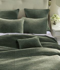 a bed with green bedspread and pillows