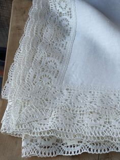 two pieces of white lace sitting on top of a wooden table