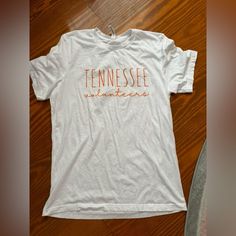 a white t - shirt with the word tennessee on it sitting on top of a wooden floor