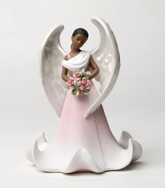 an angel figurine holding a bouquet of flowers on top of a white table