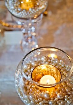 a candle that is inside of a glass bowl with pearls on the bottom and candles in it