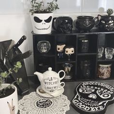 there are many halloween themed items on the shelf in this room, including teapots and mugs