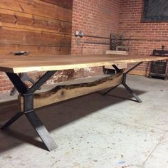 a large wooden table sitting in front of a brick wall with metal legs and an iron base