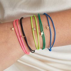 four different colored bracelets on a woman's arm with gold stars and beads