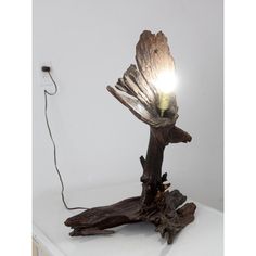 a light that is sitting on top of a wooden branch with a cord attached to it