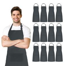 a man standing with his arms crossed in front of an assortment of black aprons