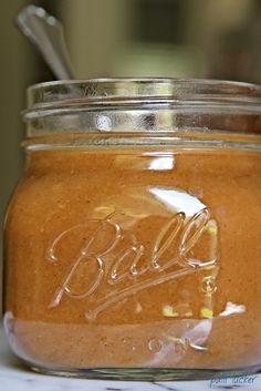 a glass jar filled with liquid sitting on top of a white counter next to a metal spoon