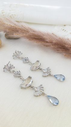 three pairs of earrings sitting on top of a white cloth next to a brown feather