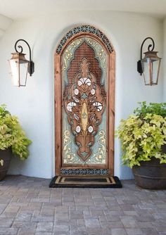 an ornate wooden door on the side of a building with potted plants in front