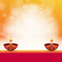 two diya candles with sparkles on top of a red brick wall in front of an orange and yellow background