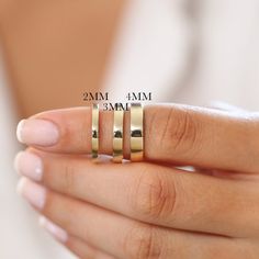 a woman's hand with three gold rings on her finger and the other two are in