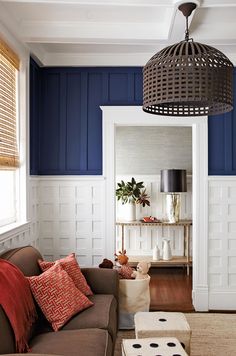 a living room with blue walls and white paneling, an open door leading to the kitchen