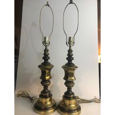 two antique brass candlesticks are sitting on a white surface with a light in the background