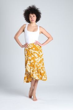 Lovely yellow floral crossover skirt, perfect for any occasion. You can pair it with sneakers for a sporty look or dress it up with heels and a special top. This crossover skirt fastens with a custom button and adjustable straps attached to the skirt, allowing you to adjust it perfectly to your waist. The floral print is a timeless classic that never goes out of style. These types of skirts are wardrobe essentials that everyone should have. Each skirt is handmade and tailored to ensure you feel Floral Print Tiered Skirt For Beach Season, Beach Asymmetrical Skirt With Floral Print, Floral Print Wrap Skirt For Vacation, Yellow Flowy Ruffled Maxi Skirt, Flowy Yellow Ruffled Maxi Skirt, Yellow Summer Beach Skirt, Floral Print Long Skirt For Beach Season, Yellow Beach Skirt For Summer, Yellow Maxi Skirt For Summer Beach Outings