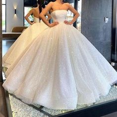 two women in wedding gowns standing next to each other with their hands on their hips