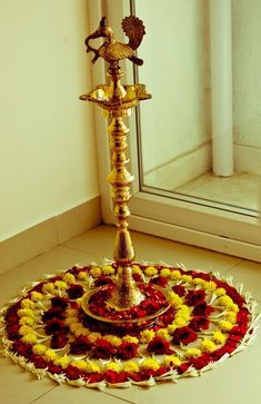 a gold and red flower arrangement on the floor in front of a window