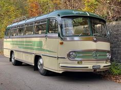 an old bus is parked on the side of the road in front of a stone wall