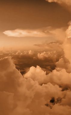 the sky is filled with clouds and brown hues in sepia toned photograph taken from an airplane window