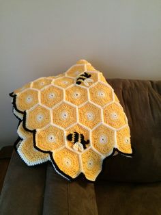 a crocheted blanket sitting on top of a couch next to a brown pillow