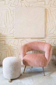 a pink chair and ottoman in front of a wall