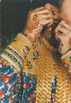 a woman with henna on her hands covering her face