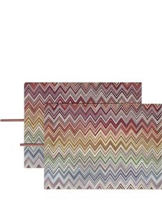 two placemats with multicolored chevron pattern on them, one is folded and the other has a brown handle