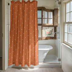 an orange shower curtain with white polka dots on it in front of a bathtub