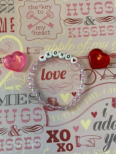 two bracelets with hearts and beads on top of a wallpaper covered in words