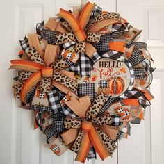 a hello fall wreath on the front door with an orange and black bow hanging from it