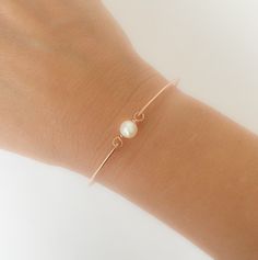 "A small & dainty white cultured freshwater pearl will be transformed into a simple cultured freshwater pearl bangle bracelet with bangle band choice of 14k rose gold filled, 14k gold filled or sterling silver, This cultured freshwater pearl bangle bracelet makes for the perfect minimalist bridesmaid bracelet, simple bridal bracelet, or an everyday simple bracelet. Personalize this simple bangle bracelet with custom initial charms to make personalized bridesmaid bangle bracelets; http://www. Adjustable Rose Gold Pearl Bracelet For Wedding, Dainty Rose Gold Pearl Bracelet For Formal Occasions, Minimalist Adjustable Pearl Bracelet For Anniversary, Delicate Rose Gold Pearl Bracelet, Adjustable Rose Gold Pearl Bracelet For Formal Occasions, Classic Rose Gold Pearl Bracelet For Wedding, Rose Gold Bangle Pearl Bracelet As A Gift, Adjustable Rose Gold Minimalist Pearl Bracelet, Rose Gold Bracelets With Pearl Charm For Wedding