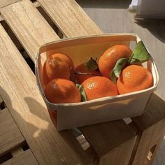 a wooden crate filled with oranges on top of a table