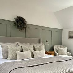 a large bed sitting in a bedroom next to two chairs and a table with a potted plant on top of it