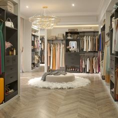 a walk in closet filled with lots of clothes and other items on shelves next to a chandelier