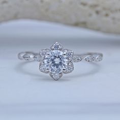 an engagement ring with a flower design on the side and diamond accents around the band